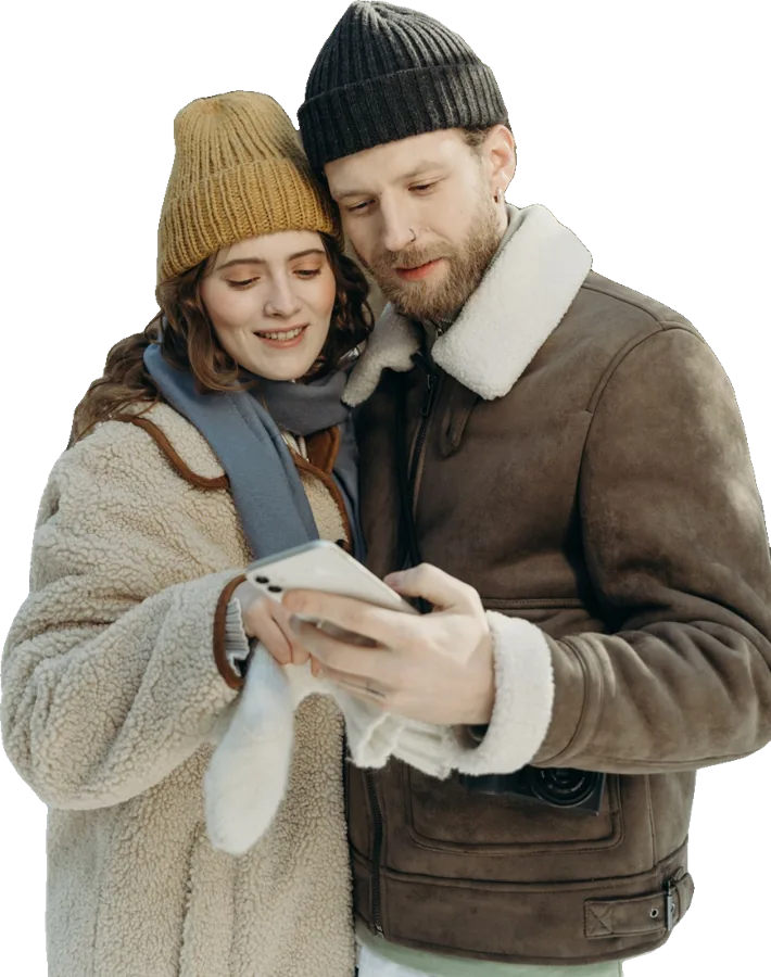 Paar in Wintermänteln schaut gemeinsam aufs Handy