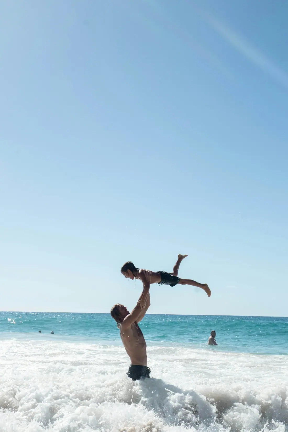 Vater wirft sein Kind im Meer in die Luft